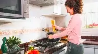 Mulher cozinhando no melhor cooktop 5 bocas